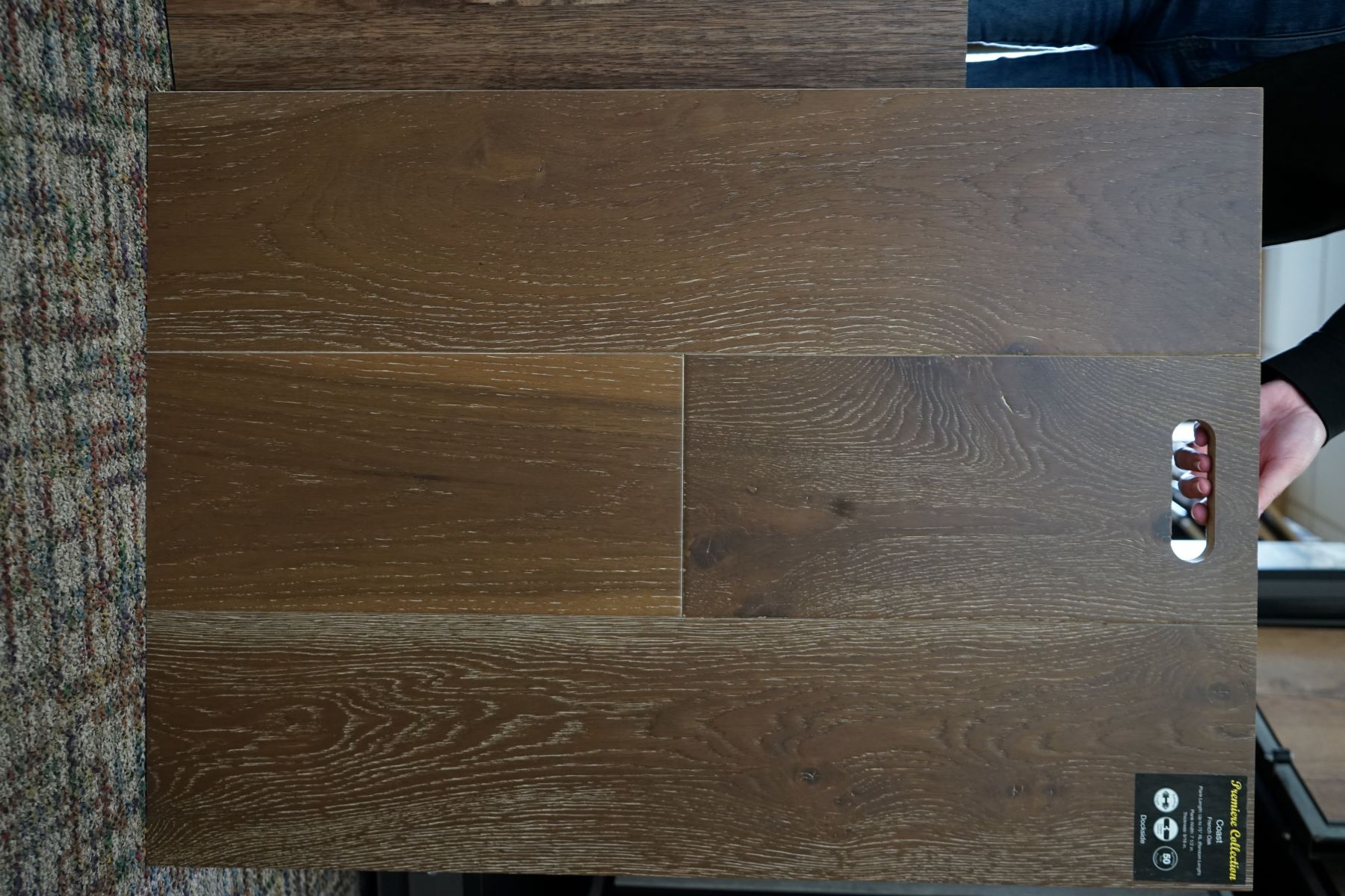 A hand holding a display sample of hardwood floor